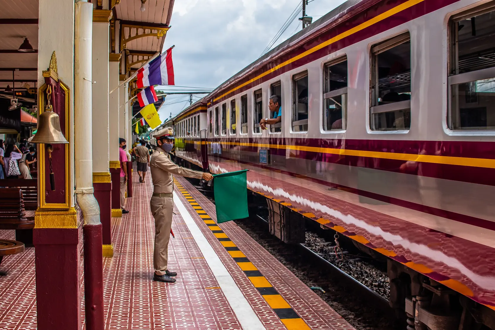 Ein Zug und ein Bahnbeamter am Bahnsteig in Ayutthaya