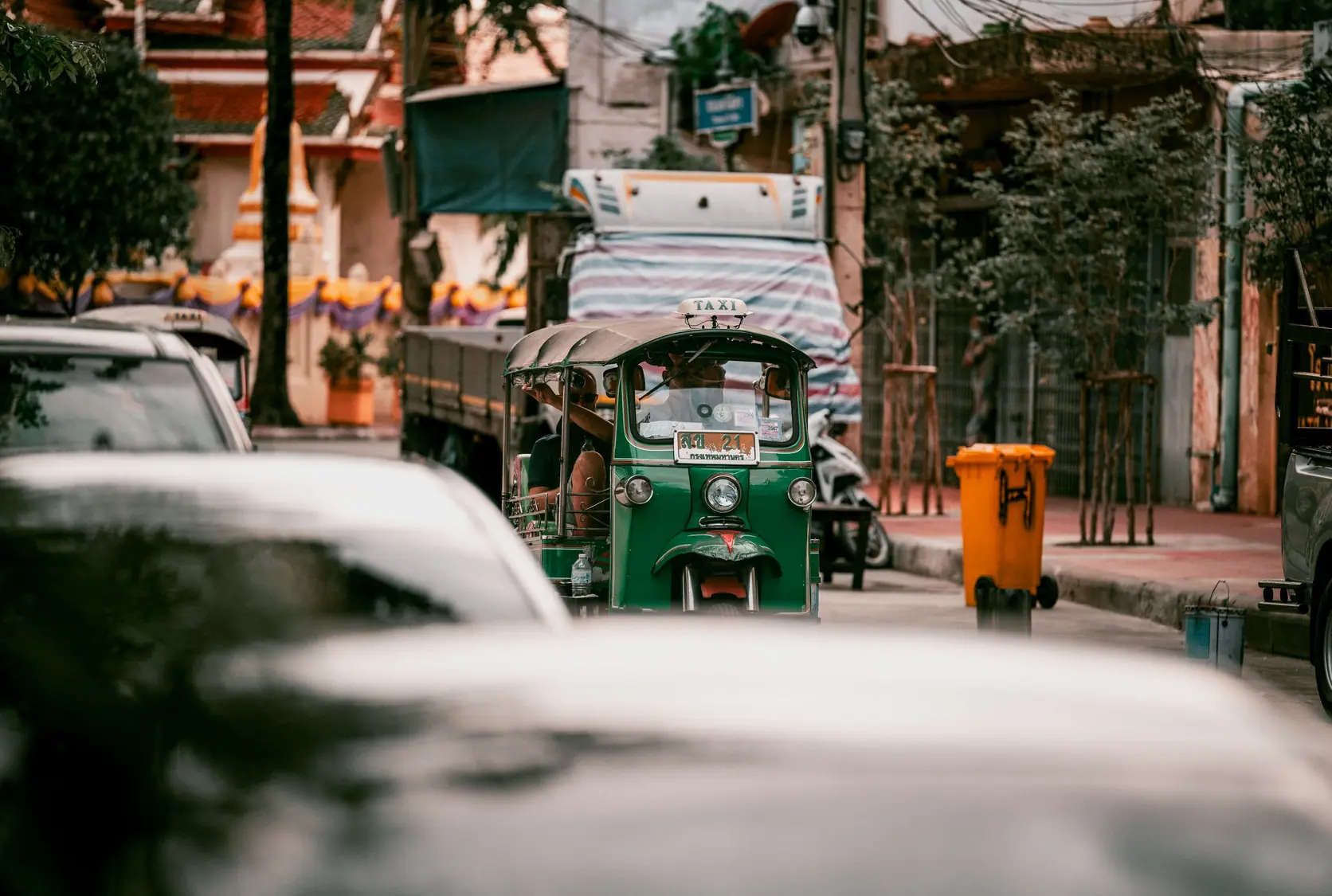 Ein grünes Tuk-Tuk im Verkehr von Bangkok