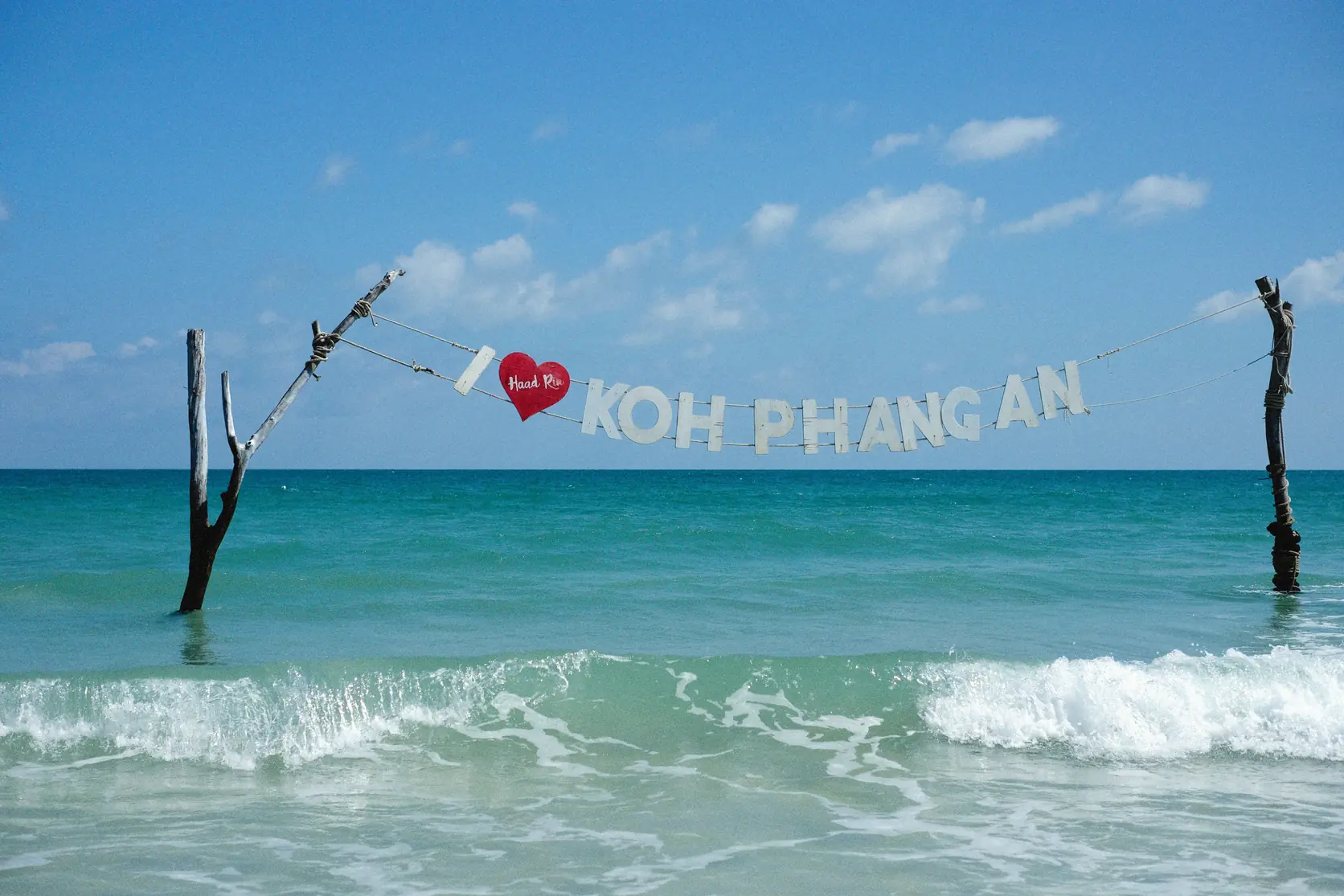 Waves and a Koh Phangan sign on the shore