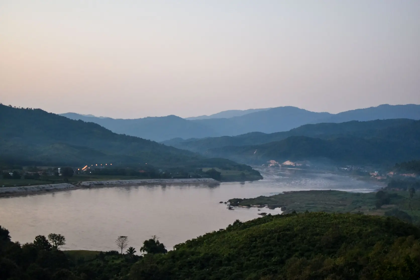 夕暮れの森の丘の間を流れるメコン川