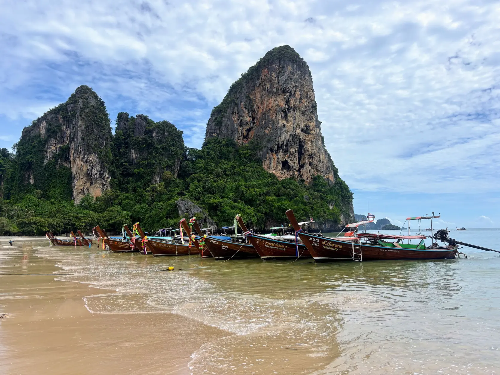 Longtailboote am Railay Beach unter Kalksteinfelsen